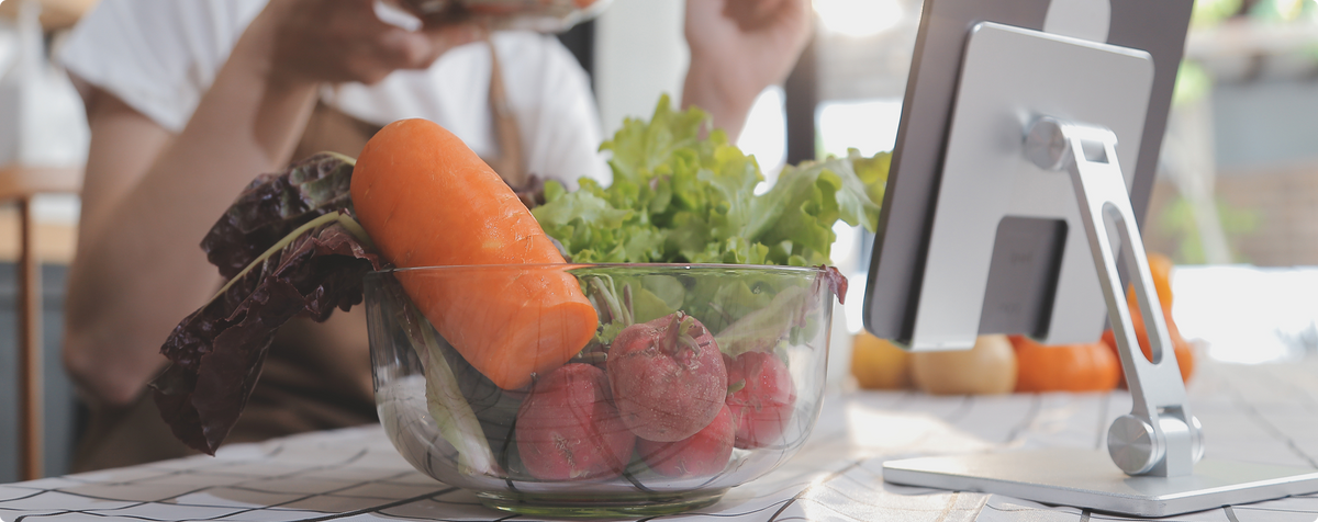 Fresh vegetables in a glass bowl with a tablet for healthy meal planning